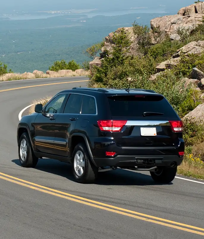 tinted windows on SUV driving around bend overlooking ocean